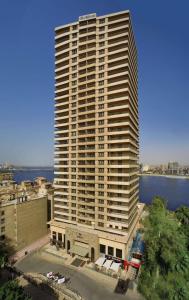 a tall white building with a river in front of it at Hilton Cairo Zamalek Residences in Cairo