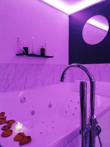 La salle de bains est pourvue d'une baignoire blanche avec un éclairage violet. dans l'établissement L'Atelier de rêves, à Metz