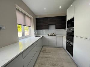 cocina con armarios blancos, fregadero y ventana en Star London Bell Lane 3-Bed Oasis with Garden en Hendon