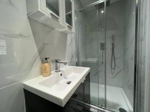 a white bathroom with a sink and a shower at Star London Bell Lane 3-Bed Oasis with Garden in Hendon