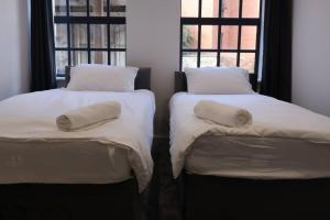 two beds sitting next to each other with pillows on them at Modern house in Birmingham in Birmingham