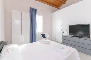 um quarto branco com uma televisão e uma cama em Casa Ancora TownHouse em Catânia