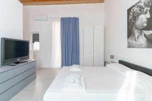 ein weißes Schlafzimmer mit einem großen Bett und einem TV in der Unterkunft Casa Ancora TownHouse in Catania