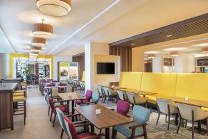 a restaurant with tables and chairs and a yellow wall at Hampton By Hilton Dubai Airport in Dubai