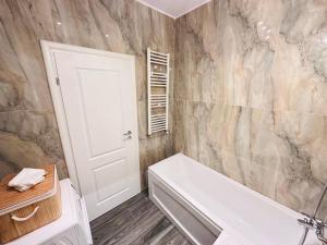 a bathroom with a white tub and a marble wall at RHUM B02 - Liberty in Bucharest +9 photos