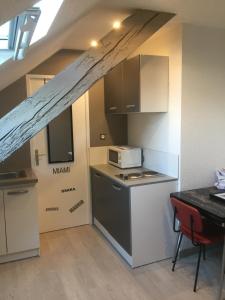 a small kitchen with a stove and a microwave at Studio moderne, étage 3, avec literie de qualité prémium in Belfort