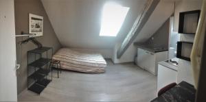 a small attic room with a bed and a window at Studio moderne, étage 3, avec literie de qualité prémium in Belfort