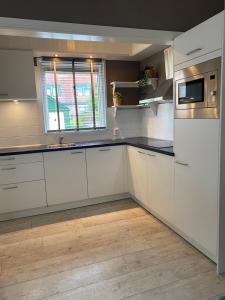a white kitchen with white cabinets and a window at Free Fly Loft Drachten in Drachten