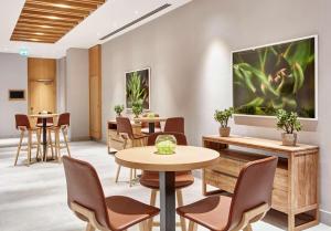 a waiting room with tables and chairs and a large painting on the wall at Hilton Garden Inn Dubai, Mall Avenue in Dubai