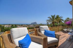 2 chaises en osier assises sur une terrasse en bois dans l'établissement Villa La Perla Calpe with Seaview & large pool, à Calp