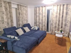 un divano blu in soggiorno con tende di Remarkable 1-Bed Apartment in Dartford a Dartford