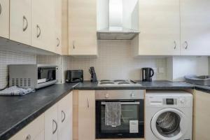 ロンドンにあるAPlaceToStay Central London Apartment, Zone 1 PICのキッチン(白いキャビネット、洗濯機、コンロ付)