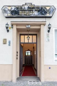 a sign over the door of a building with a red carpet at Ferienwohnungen Marquardt in Berlin