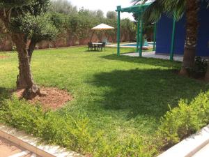 zielony dziedziniec ze stołem i drzewem w obiekcie VILLA TAZARZIT w Marakeszu