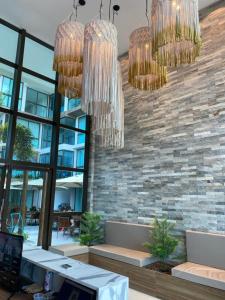 a lobby with chandeliers and a stone wall at Sunny Hall Porto de Galinhas PE - Flat Piscina Privativa in Porto De Galinhas