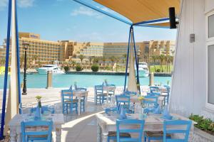 a patio with tables and chairs and a pool at Hilton Hurghada Plaza Hotel in Hurghada