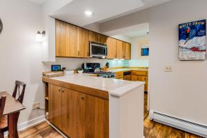 cocina con armarios de madera y encimera en Skihaven East Glade A1, en Killington