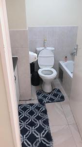 baño con aseo y alfombra blanca y negra en Menlyn Place Staycation, en Pretoria