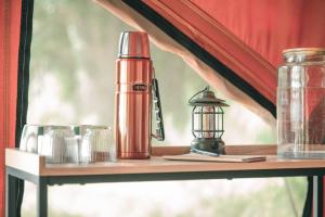 a table with a red thermos and a lantern on it at Les Toiles du Cassis 