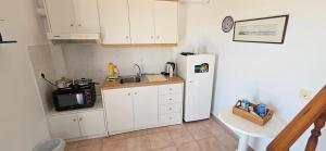 een keuken met een witte koelkast en een wastafel bij Ra's Seacastle in Tsoútsouros
