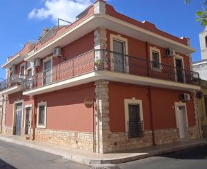 a red house with a balcony on a street at Apartment da Rosa in San Vito dei Normanni