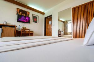 a large white bed in a room with a desk at Hostellerie de la Sanaga in Edéa