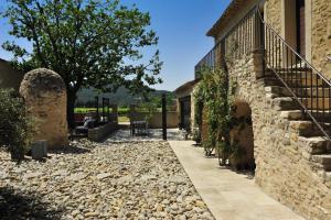 una pasarela fuera de una casa con una pared de piedra en Le Jour et la Nuit, Maison d'hôtes, en Vaison-la-Romaine