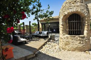 a patio with a stone building with chairs and tables at Le Jour et la Nuit, Maison d'hôtes in Vaison-la-Romaine