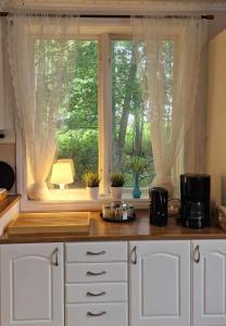 eine Küche mit einer Theke und ein Fenster mit Vorhängen in der Unterkunft Berggården Vandrarhem in Gnarp