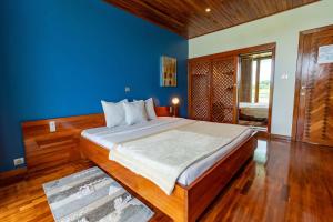 a bedroom with a large bed with a blue wall at Hostellerie de la Sanaga in Edéa