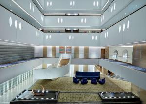 a lobby with a staircase and blue chairs at Hilton Garden Inn Muscat Al Khuwair in Muscat