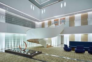 a lobby with a staircase and blue chairs at Hilton Garden Inn Muscat Al Khuwair in Muscat