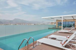 uma piscina com duas espreguiçadeiras no topo de um edifício em Hilton Garden Inn Muscat Al Khuwair em Mascate