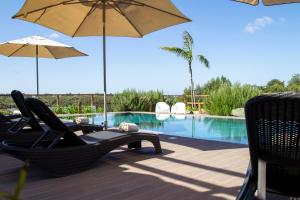 two chairs and umbrellas next to a swimming pool at Quinta da Relva - Soulful House in Mafra