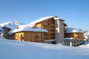 a building covered in snow with snow covered roofs at Sun Valley Residence in La Plagne