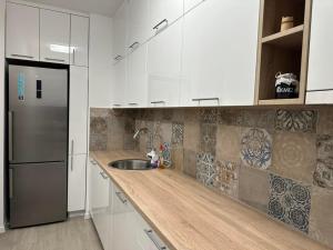 a kitchen with white cabinets and a stainless steel refrigerator at Novouređen stan u Vitezu in Vitez