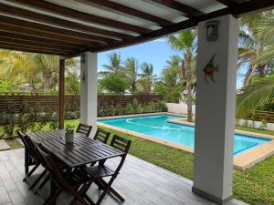 a patio with a table and chairs next to a swimming pool at CASA MOZITA in Vilanculos