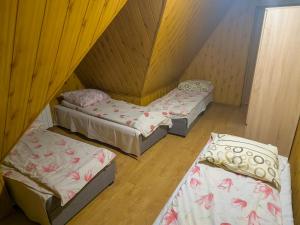 three beds in a room with wooden walls and wooden floors at uAntosi Małe Ciche in Murzasichle