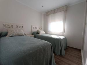 a bedroom with two beds and a window at Preciosa casita a 10 minutos de la playa. in Cangas de Morrazo