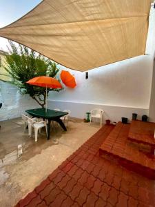 eine Terrasse mit einem Sonnenschirm, einem Tisch und Stühlen in der Unterkunft Casa agradable el Cañavate in El Cañavate