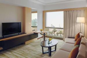 uma sala de estar com um sofá e uma televisão em DoubleTree by Hilton Hotel Riyadh - Al Muroj Business Gate em Riyadh