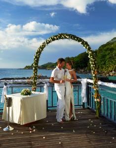Ein Mann und eine Frau stehen unter einem Bogen in der Unterkunft Hilton Seychelles Northolme Resort & Spa in Beau Vallon