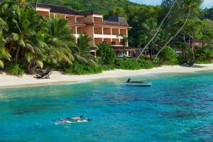 una persona nadando en el agua junto a una playa en DoubleTree by Hilton Seychelles Allamanda Resort & Spa, en Takamaka