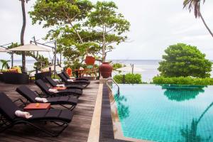 a row of lounge chairs next to a swimming pool at DoubleTree by Hilton Seychelles Allamanda Resort & Spa in Takamaka