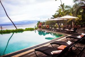 a pool at a resort with chairs and a beach at DoubleTree by Hilton Seychelles Allamanda Resort & Spa in Takamaka