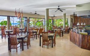 a restaurant with tables and chairs and a bar at DoubleTree by Hilton Seychelles Allamanda Resort & Spa in Takamaka