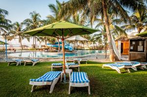 un grupo de sillas y una sombrilla junto a una piscina en Hilton Salalah Resort, en Salalah