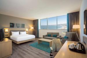 Hilton Garden Inn Tanger City Centre في طنجة: فندق غرفه بسرير وصاله سرير واريكه