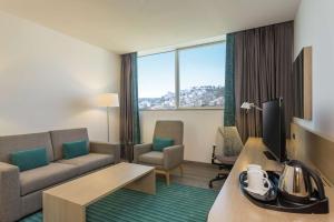 - un salon avec un canapé et une télévision dans une chambre d'hôtel dans l'établissement Hilton Garden Inn Tanger City Centre, à Tanger