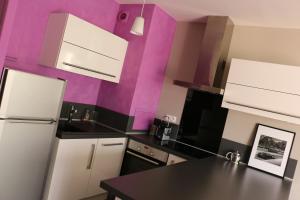 kuchnia z białymi urządzeniami i fioletowymi ścianami w obiekcie Appartement Le Saint-Etienne avec Terrasse w mieście Beaune